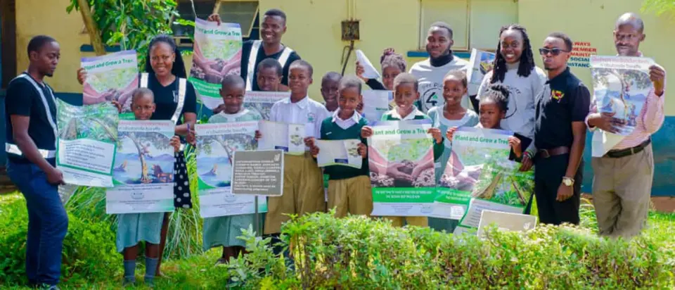 Pupils and our team holding up posters that read Plant and Grow a Tree