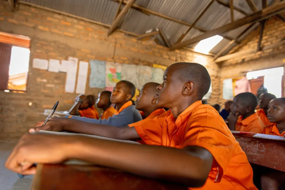 Pupils writing at their desks in a classroom in Rukungiri