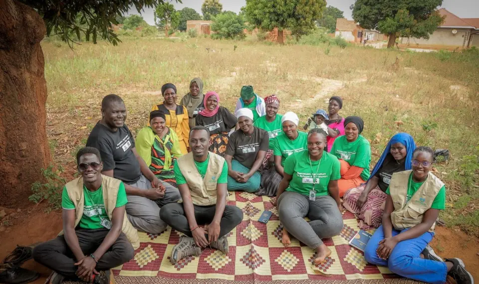 The BetterLife team sitting on a mat with a women's group