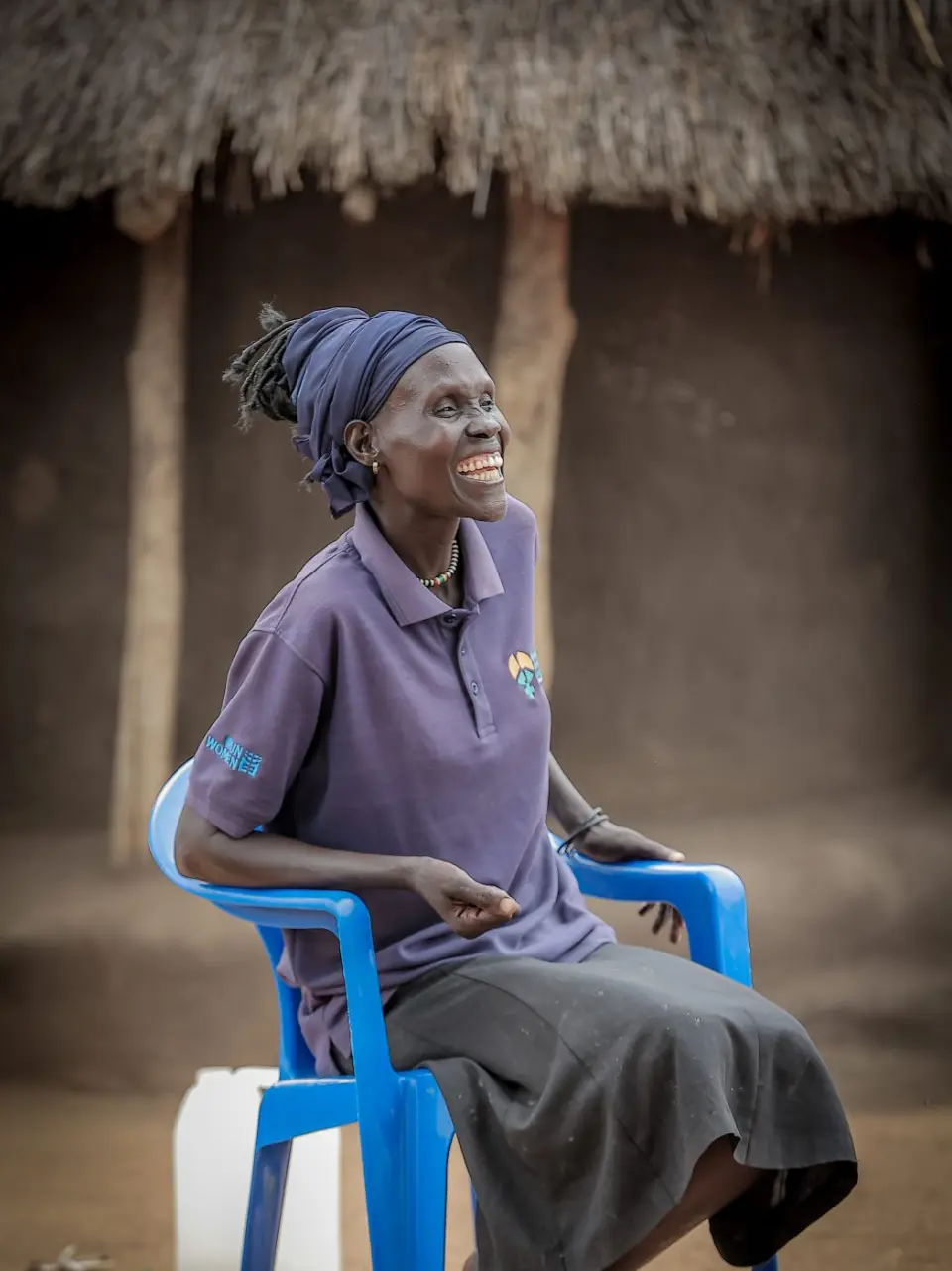 A woman laughing on a blue chair outside her home