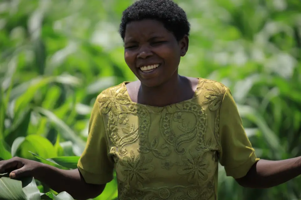 A farmer smiling among her maize in Rukungiri