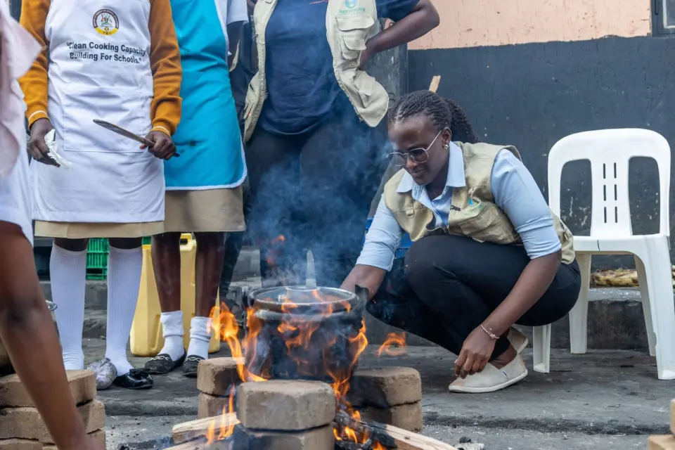 A BetterLife team member at a cooking demonstration with students in “Clean Cooking Capacity Building for Schools” aprons