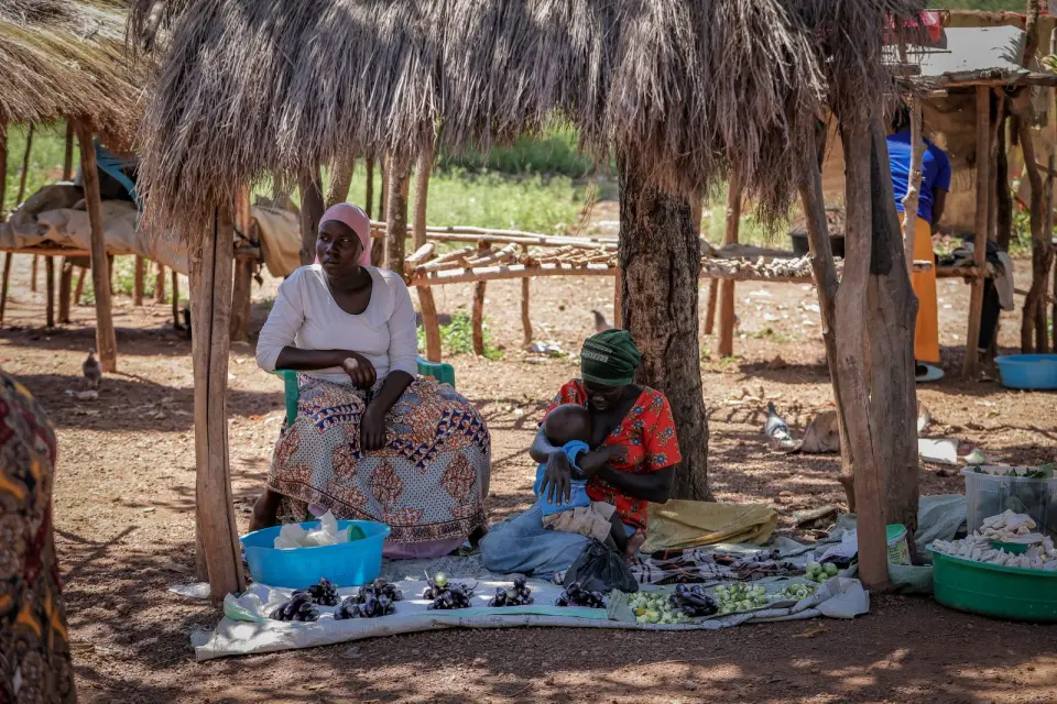 Women selling produce under a shade shelter at a market in Yumbe