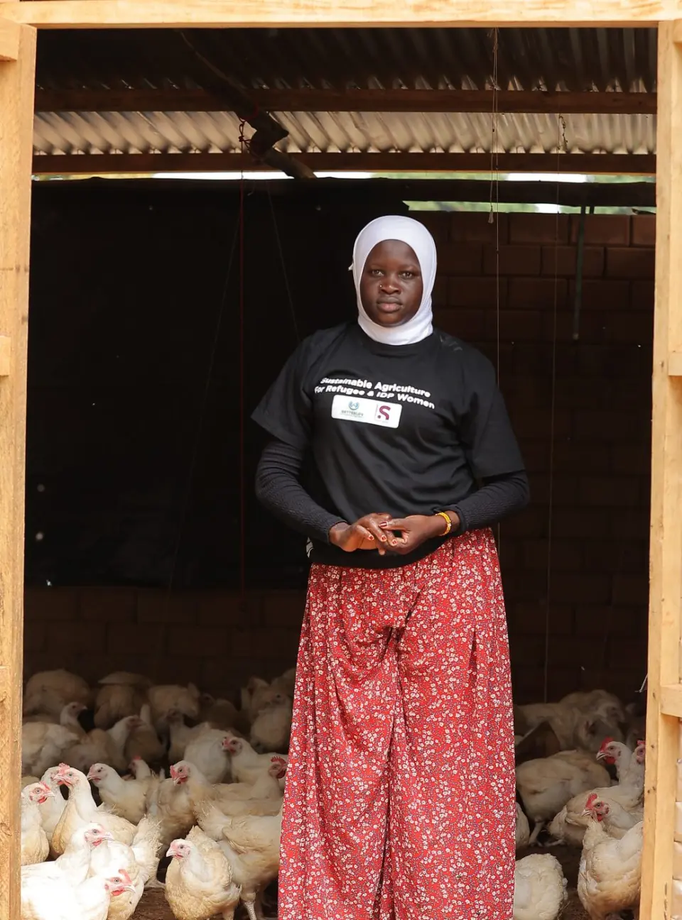 A woman standing in the doorway of her poultry house in Yumbe