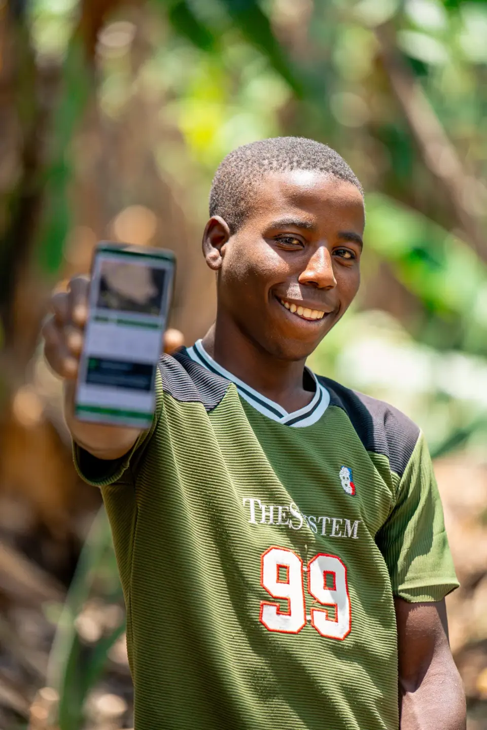 A young man holding up a phone showing the Soilla app